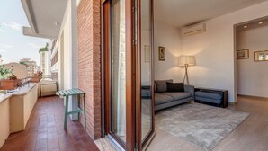 Un balcon avec une porte-fenêtre coulissante, une petite table et des plantes en pot.