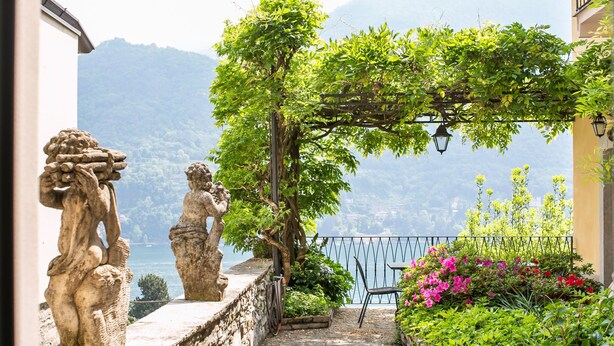 Un chemin de pierre mène à une terrasse d’où l’on peut admirer un lac et des montagnes.
