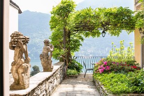 A stone pathway leading to a terrace with a view of a lake and mountains. - Appartamento Fioravante by Wonderful Italy (Moltrasio)