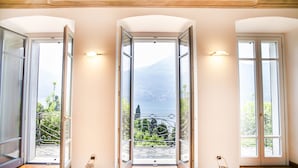 L’entrée d’un hôtel, avec trois portes ouvertes donnant sur des balcons d’où l’on peut admirer la verdure et les montagnes.