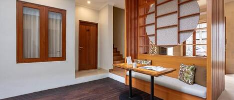Un interior moderno con piso de madera, una zona de estar con una mesa y vistas a una escalera.