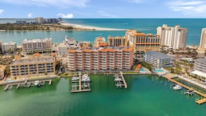 A coastal hotel with multiple buildings, a marina with boats, and a beach in the background.