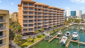 A multi-story hotel with balconies, a marina with boats, and a clear blue sky.