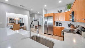 A modern kitchen with stainless steel appliances, wooden cabinets, and a marble countertop.