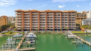 A multi-story hotel with balconies, a marina with boats, and a clear sky.