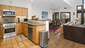 Eine moderne Küche mit Holzschränken, Edelstahlgeräten und einem Essbereich mit Sofa und Stühlen.