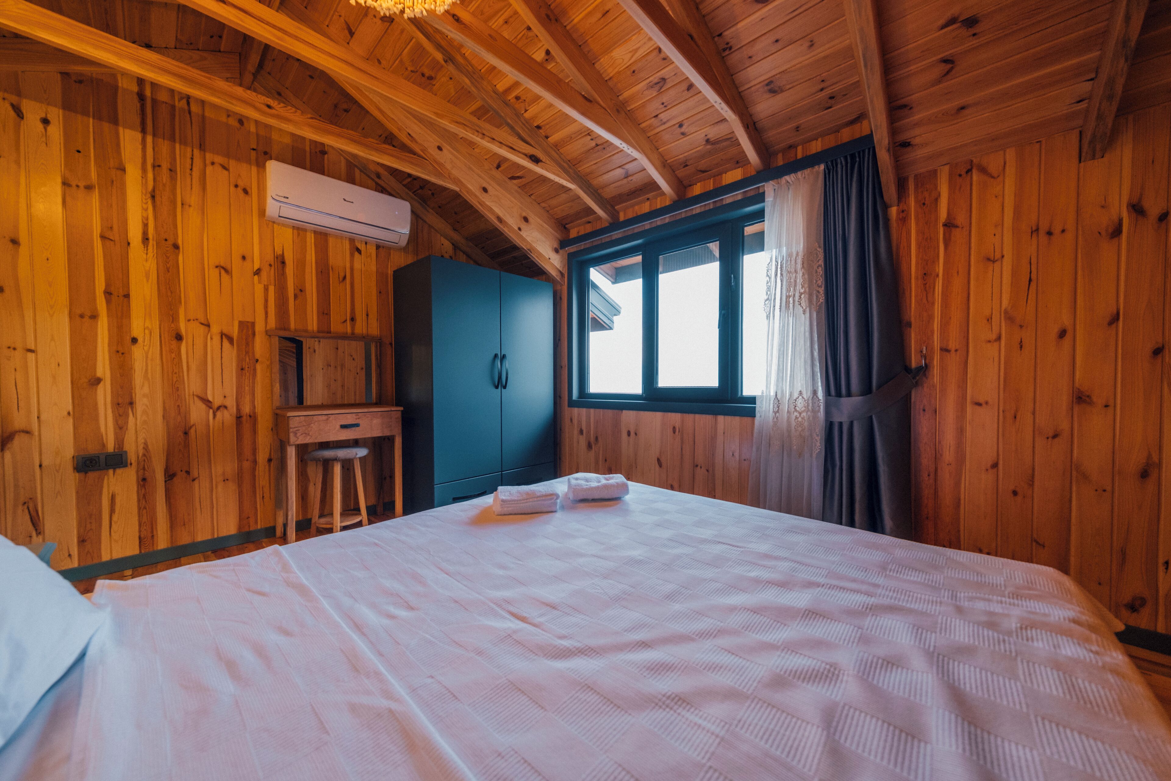 Een houten kamer met een bed, een bureau en een raam.