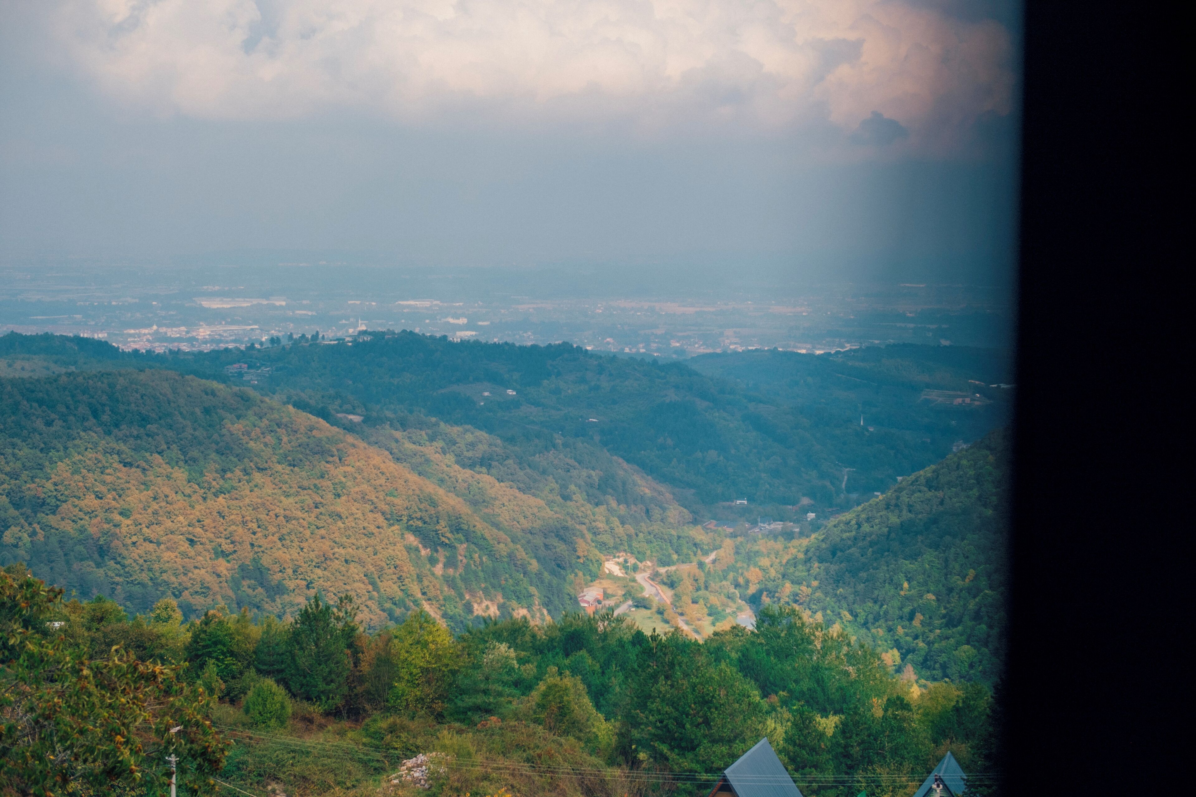A mountainous landscape with a valley and a few buildings in the foreground.