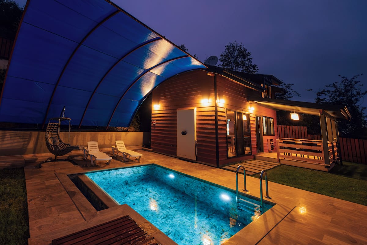 Una piscina scoperta coperta, con lettini da sole e un solarium in legno.
