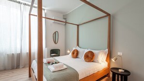 A four-poster bed with a wooden frame, a bedside table with a lamp, and a green upholstered chair. - Bazzi 49 - Università Bocconi (Milan)