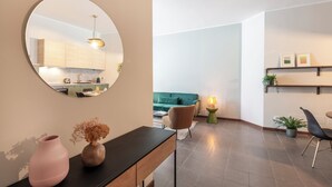 A modern living room with a round mirror, a wooden console table, a green sofa, and a dining area with a black chair. - Bazzi 49 - Università Bocconi (Milan)