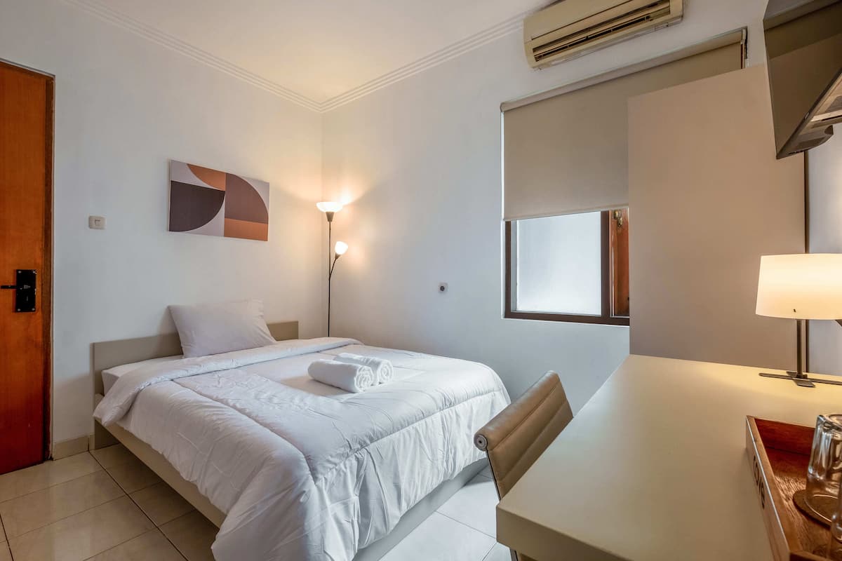 Une chambre d’hôtel équipée d’un lit, d’un bureau, d’une lampe et d’un climatiseur fixé au mur.