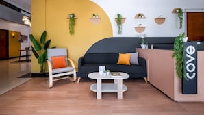 Un espace d’accueil moderne comprenant un canapé, une table basse et un comptoir de réception.