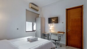 Une chambre d’hôtel avec un lit, un bureau doté d’une lampe, une porte en bois et une fenêtre.