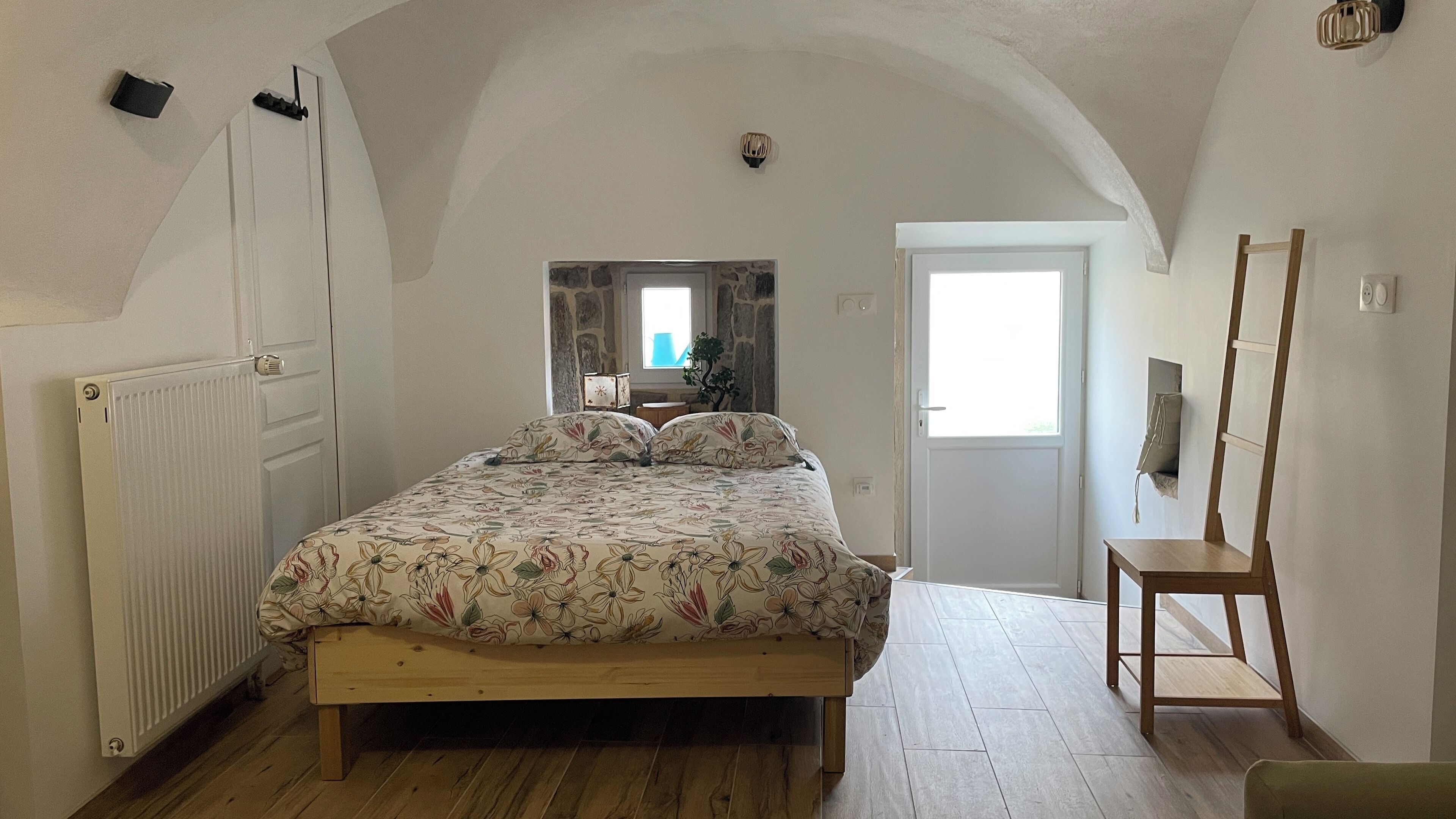 A bedroom with a wooden bed, a radiator, a wooden chair, and a window.