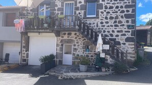 Un edificio de piedra con un garaje, una escalera y un cartel que indica una ruta turística.