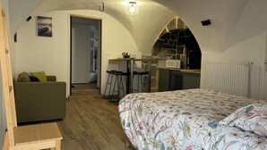 Un dormitorio acogedor con una colcha estampada con flores, un sofá verde y una mesa de madera.
