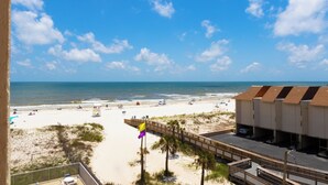 A beach view with a wooden boardwalk, beach umbrellas, and a row of beach huts.