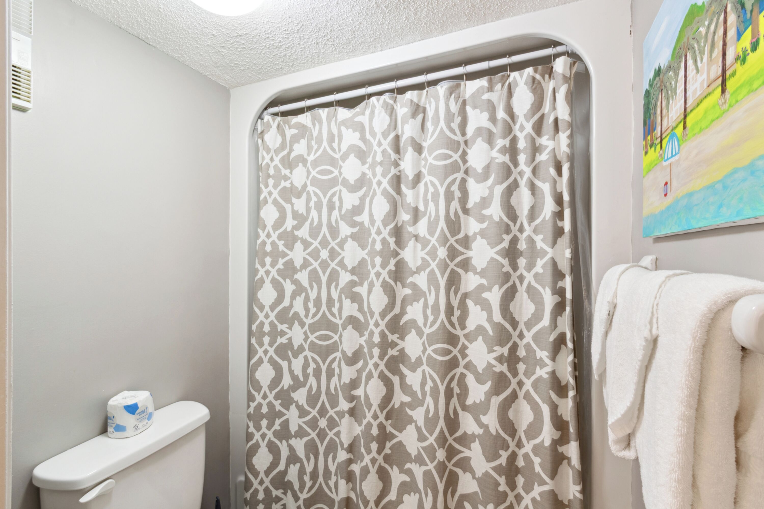 A bathroom with a shower curtain, a toilet, and a towel rack.