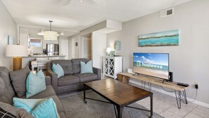 A modern living room with a sofa, coffee table, and a TV displaying 'hosteeva'.