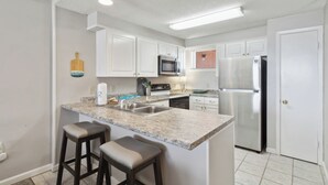 A modern kitchen with white cabinets, a granite countertop, stainless steel appliances, and a built-in island with bar stools.