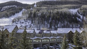 A lodge with multiple buildings, a ski slope in the background, and snow-covered trees.