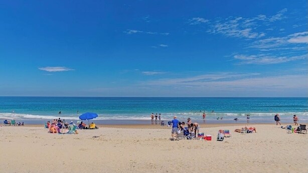 Une plage où l’on peut voir des gens bronzer, nager et se promener.