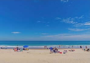 Une plage où l’on peut voir des gens bronzer, nager et se promener.