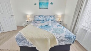 Une chambre à coucher avec un lit, deux lampes de chevet, un tableau au mur et une porte.