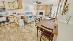 Une cuisine spacieuse avec des meubles en bois, un coin repas comprenant une table et des chaises en bois, un canapé et une cheminée.