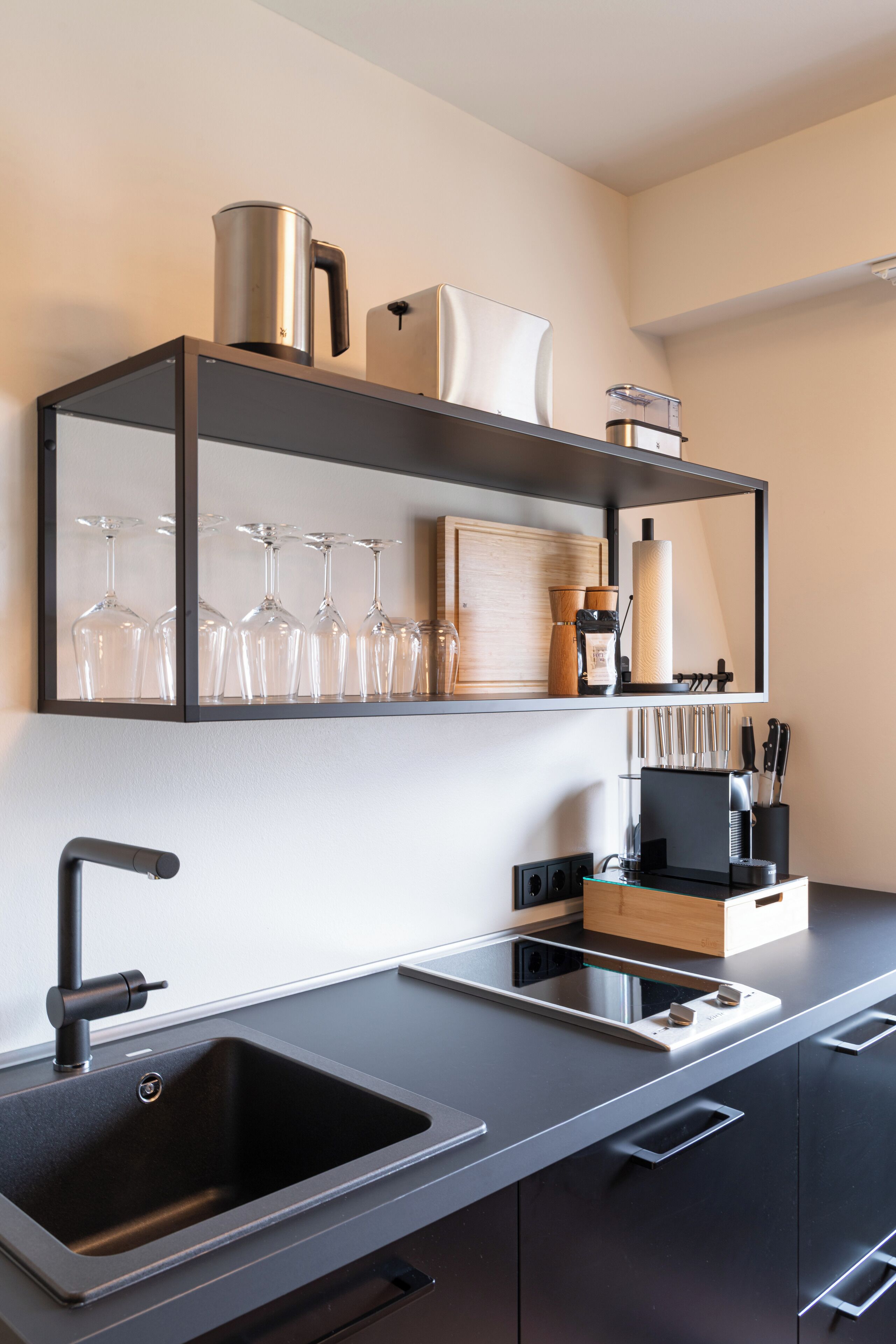 A modern kitchen with a black sink, stainless steel appliances, and a wooden countertop.