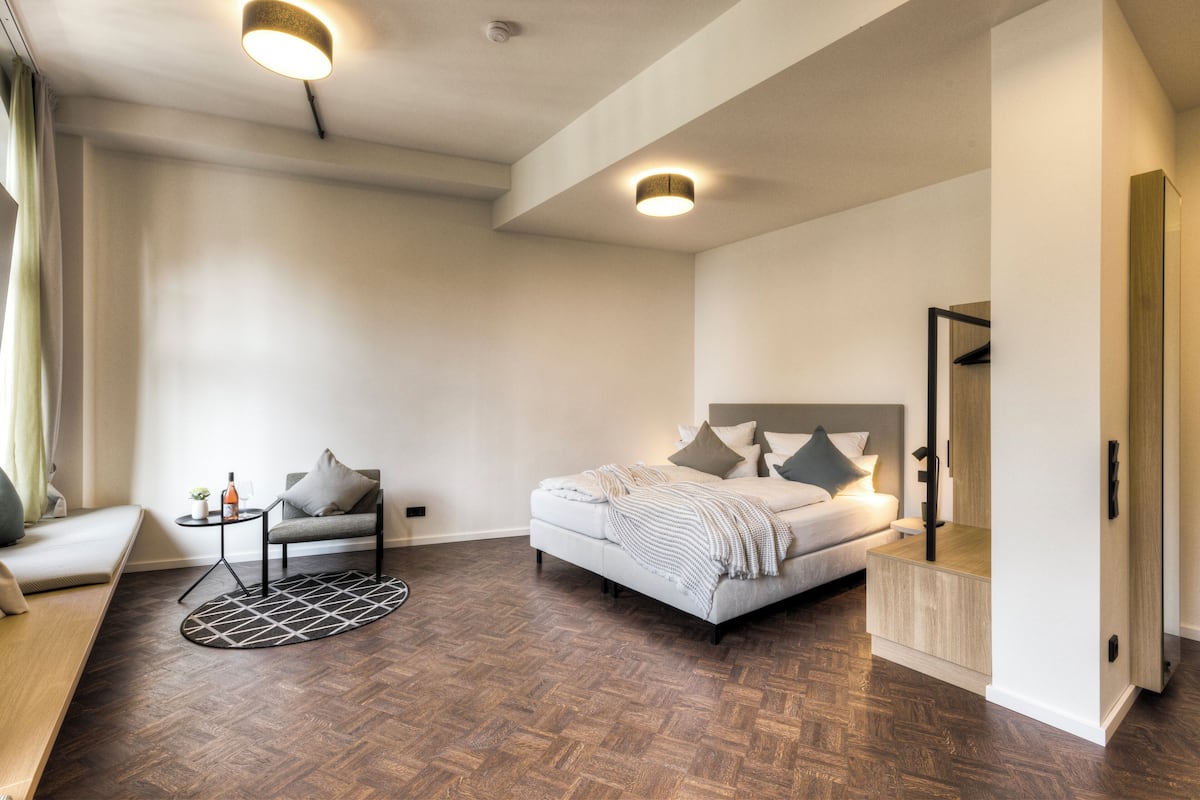 Una camera da letto moderna con un letto, comodini, una sedia e un tavolino con una pianta.