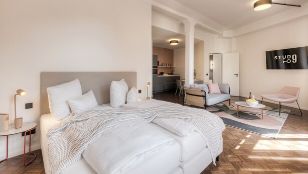 A modern hotel room with a large bed, a desk, a chair, and a TV. - Studio 9 (Fulda)