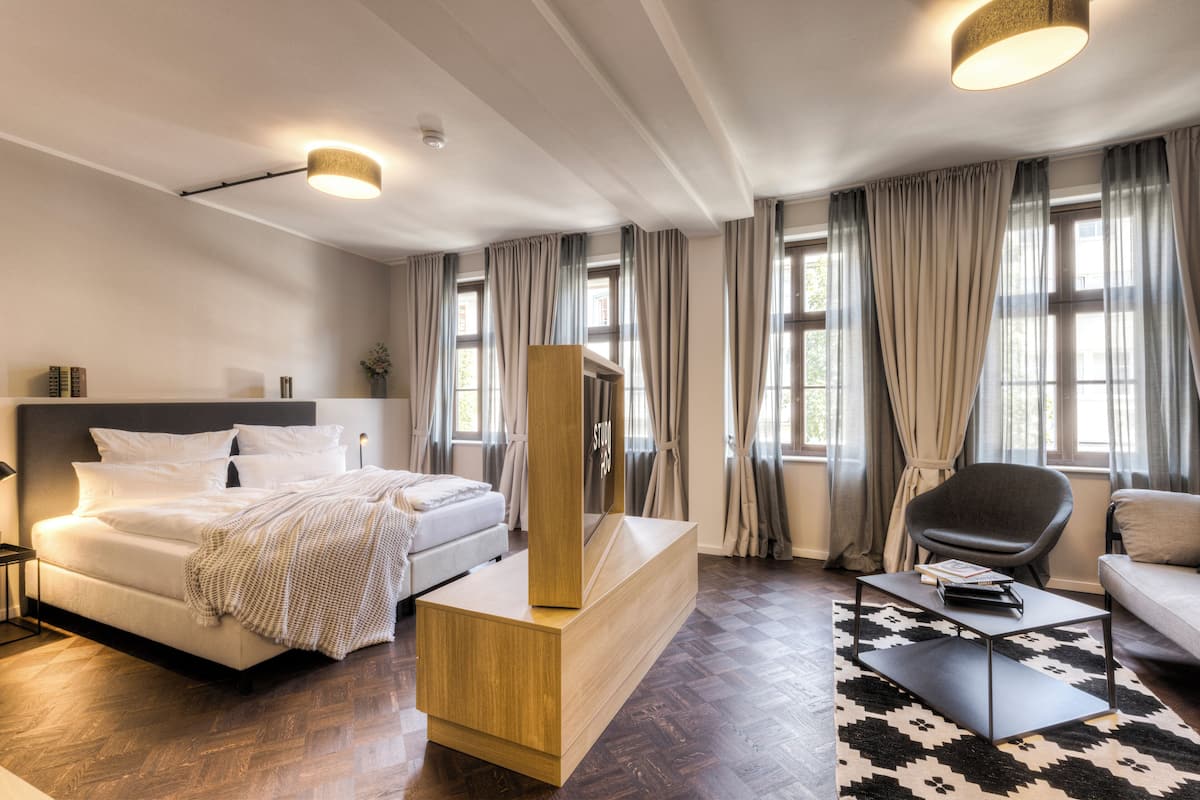 Una moderna camera d'albergo con un letto, un tavolino in legno, una poltrona e un tavolino da caffè.