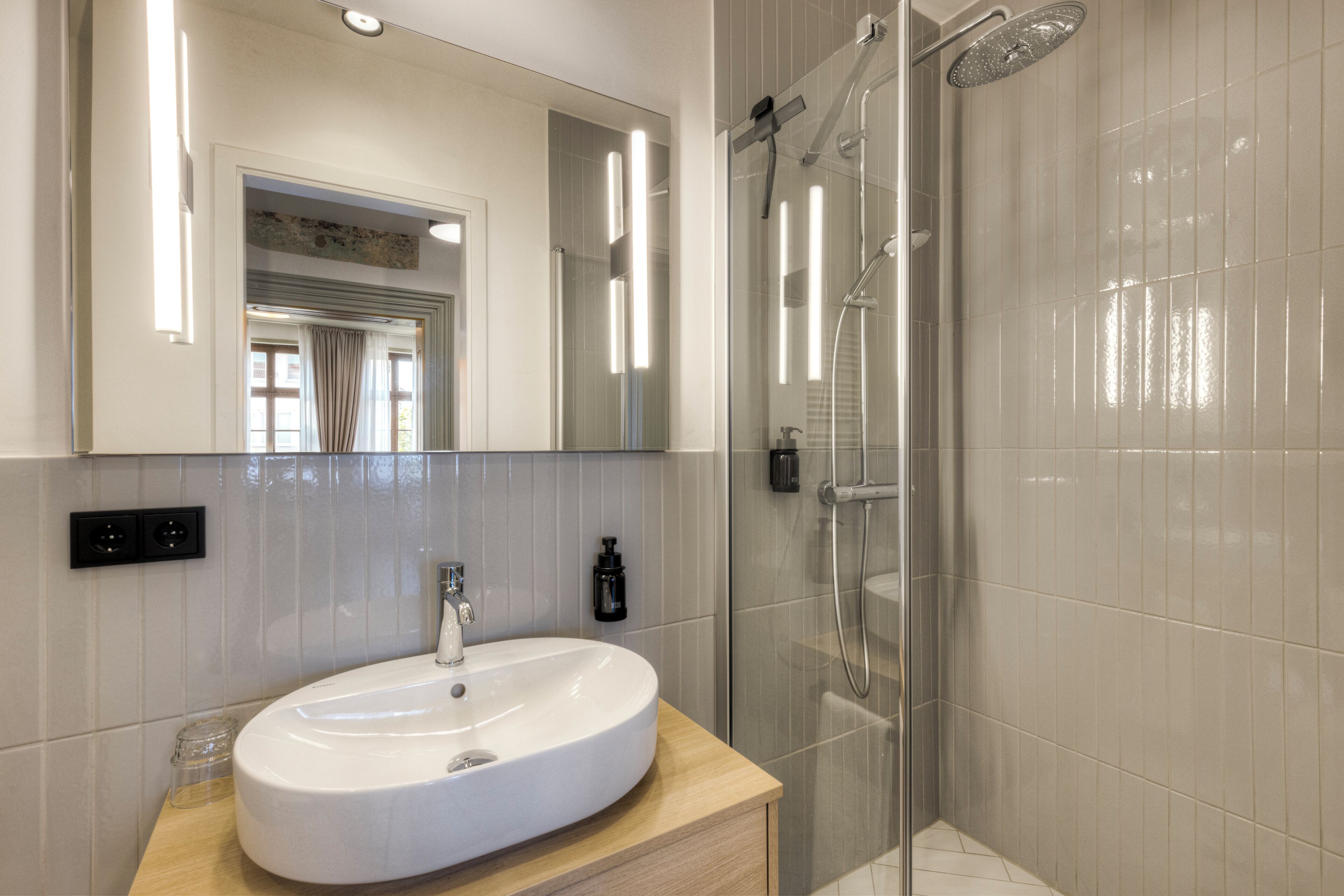 A modern bathroom with a large oval sink, a glass-enclosed shower, and a mirror above the sink.