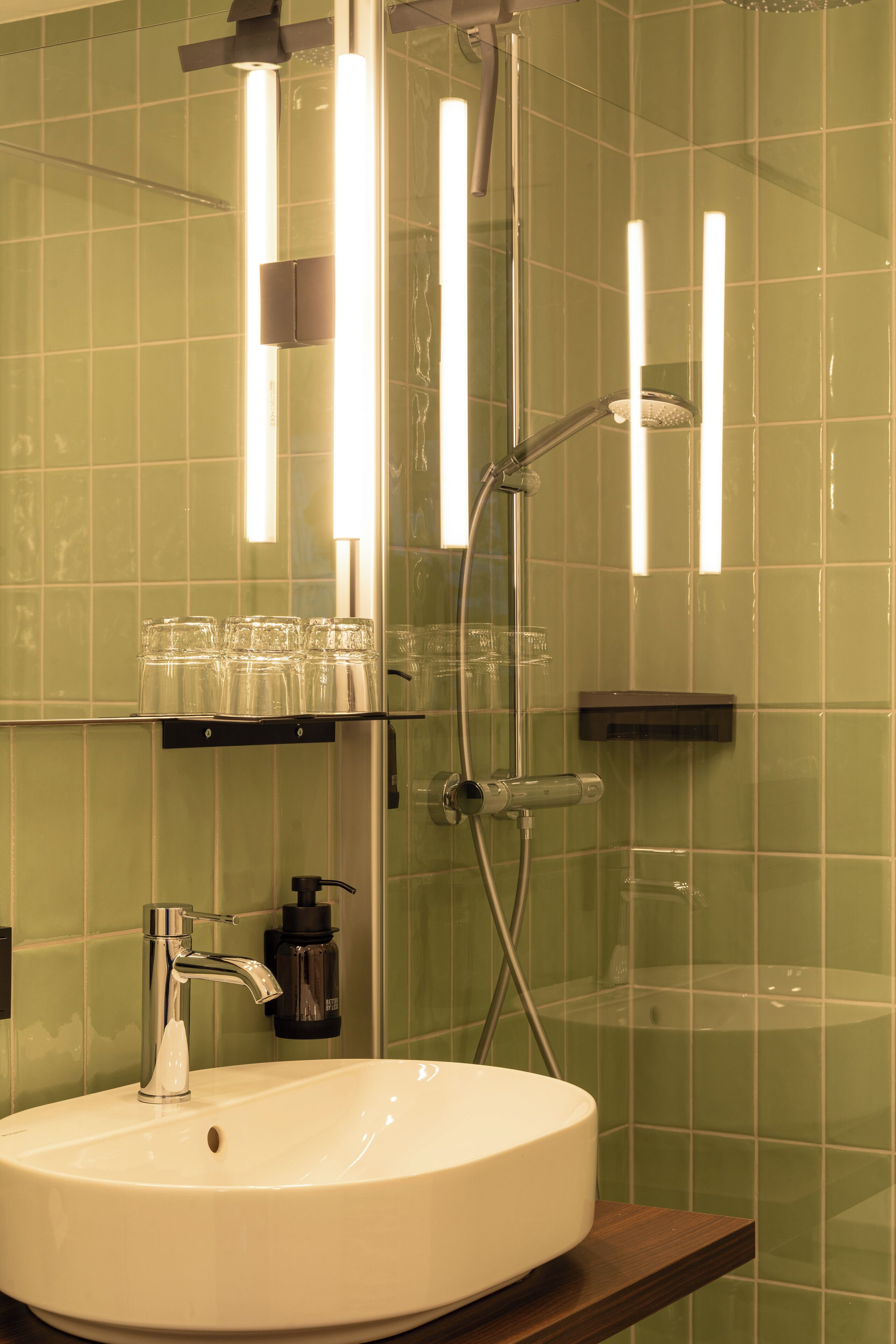 Ein Badezimmer mit einem weißen Waschbecken, einem Spiegel und einer Dusche mit Glastür.