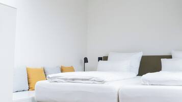 Quarto de hotel moderno com claraboia, cama com roupa de cama branca, cabeceira verde e carpete texturizado.