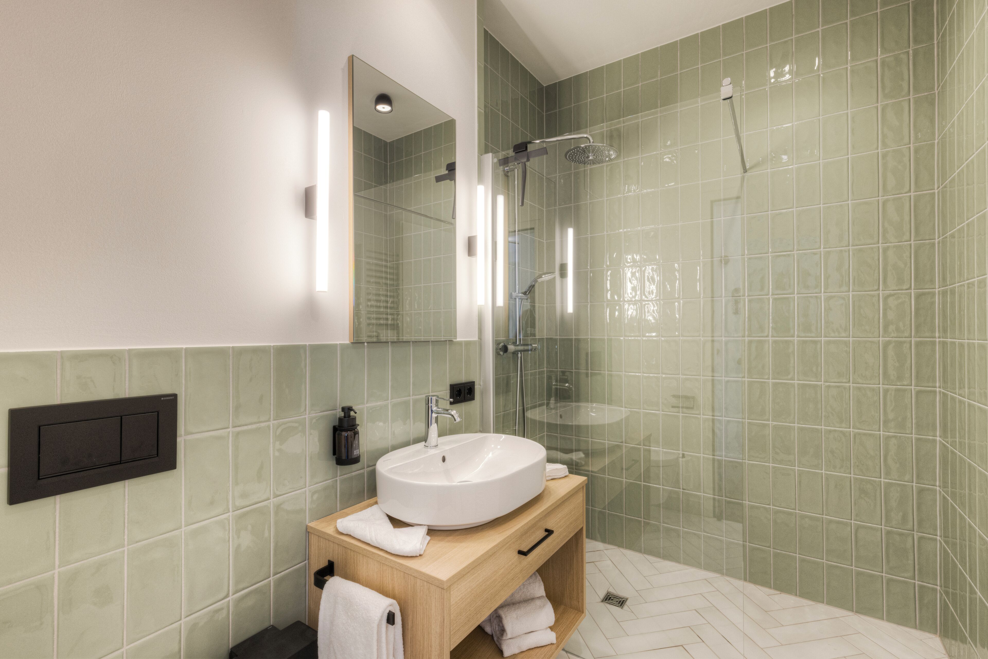 A modern bathroom with a large mirror, a round sink, and a glass-enclosed shower.