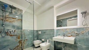 A modern bathroom with a glass shower enclosure, a bidet, a sink, and a toilet. - Relais Sampaoli  (Florence)