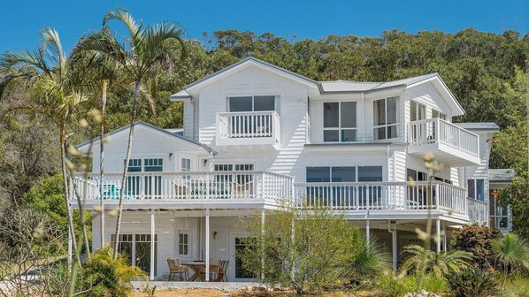 Ein Strandhaus mit zwei Etagen, mehreren Balkonen, einer Veranda und einem Pool.