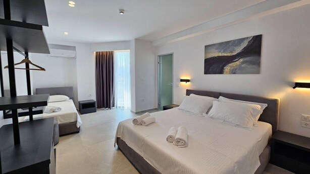 A modern hotel room with a large bed, bedside tables, a desk, and a TV. - Adele Hotel Ksamil (Ksamil)