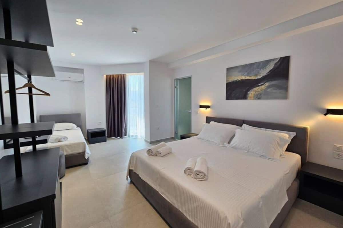 Una habitación de hotel moderna con una cama grande, mesitas de noche, un escritorio y un televisor.
