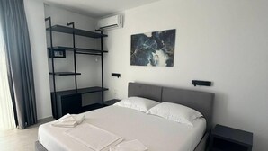 A modern hotel room with a large bed, a built-in desk, and a wall-mounted air conditioner. - Adele Hotel Ksamil (Ksamil)