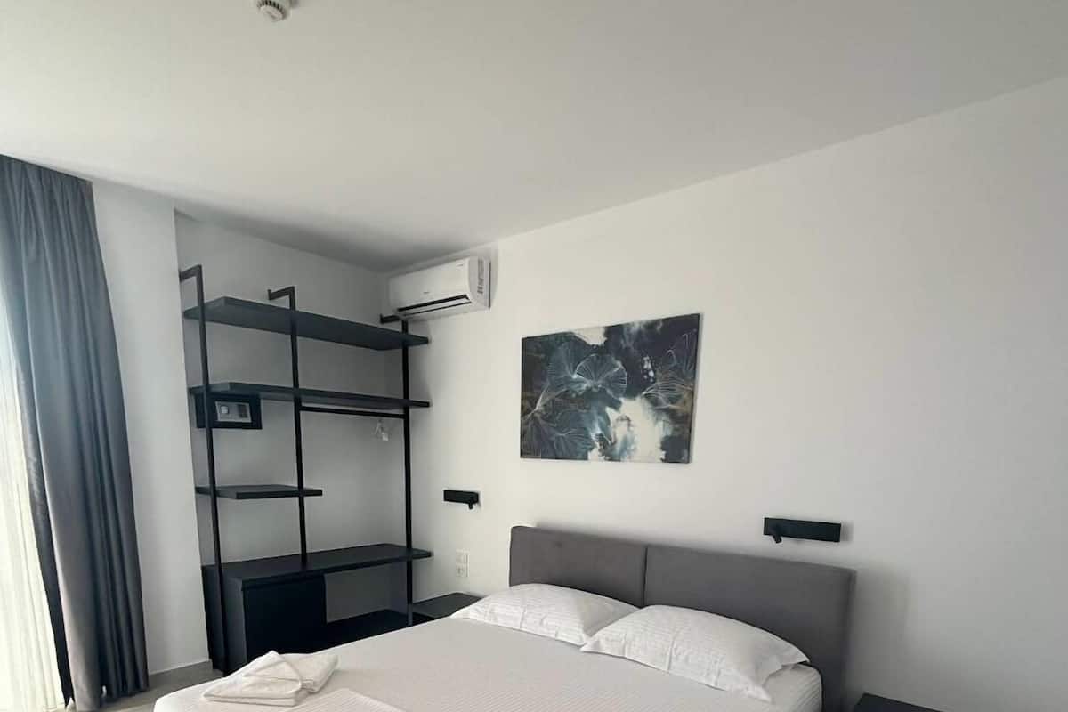 Una habitación de hotel moderna con una cama grande, un escritorio empotrado y un aire acondicionado de pared.