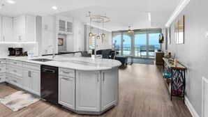 A modern kitchen with a large island, white cabinetry, and a view to the outside.