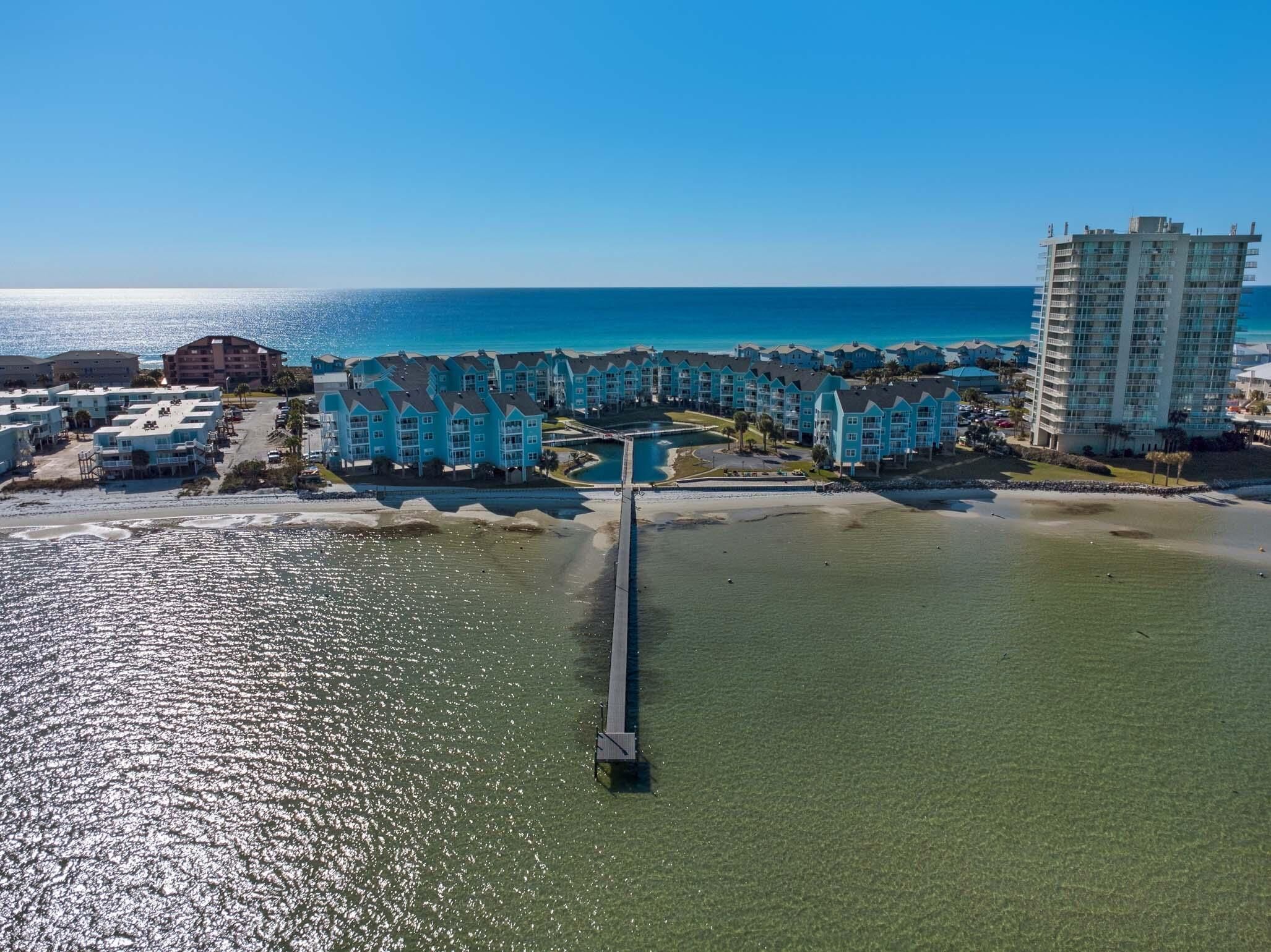 Ein Küstenhotel mit mehreren blauen Gebäuden, einer Pier, die sich ins Wasser erstreckt, und freiem Blick auf den Ozean.