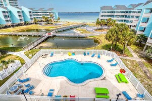 A swimming pool with lounge chairs and a view of the beach.