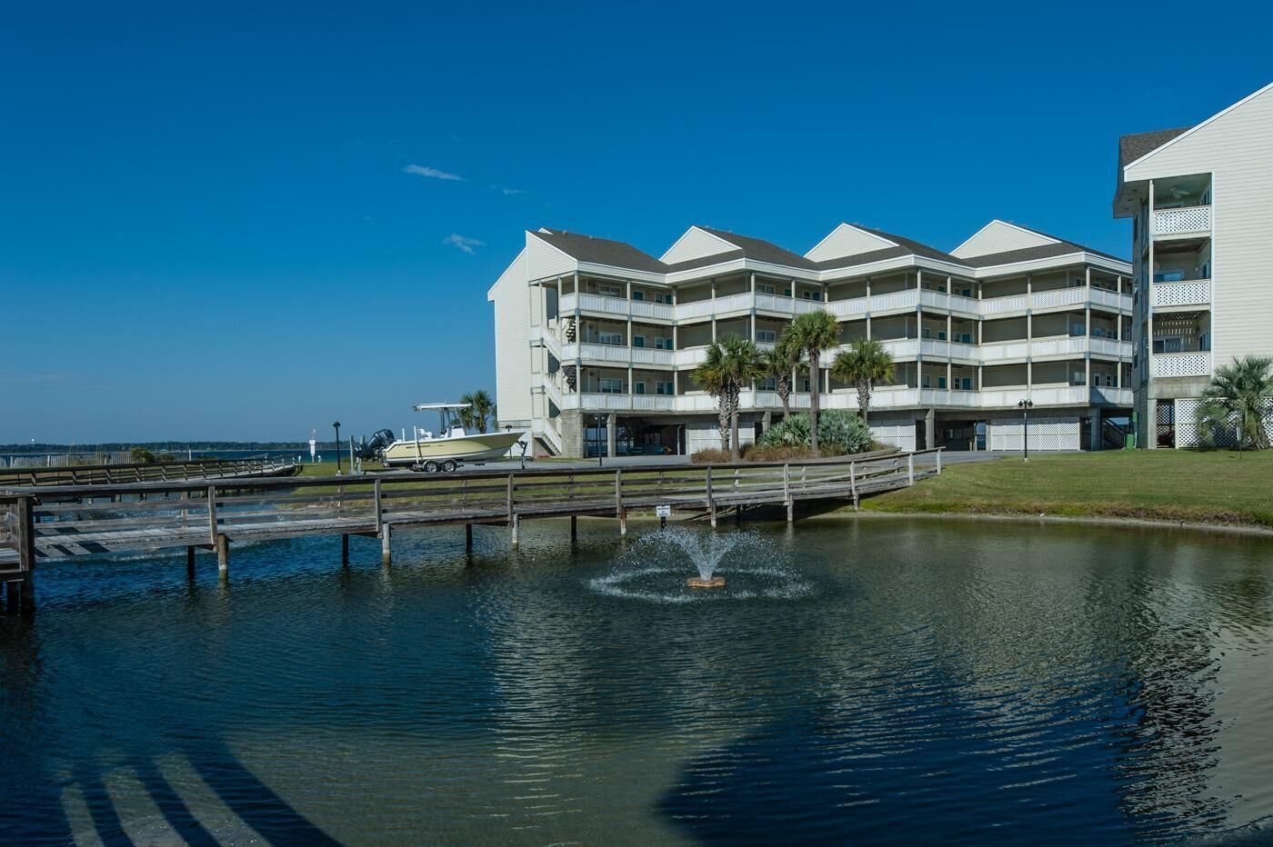 A waterfront hotel with multiple balconies, a dock, and a fountain.