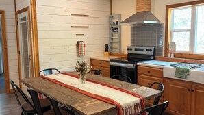 Een moderne keuken met een houten tafel, zwarte stoelen en een inbouwfornuis.