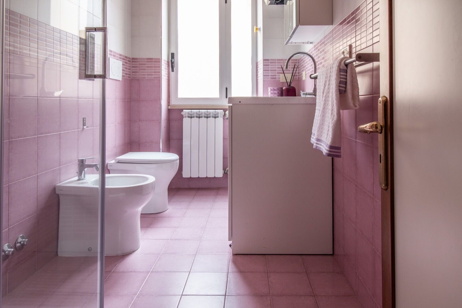 Une salle de bain avec deux toilettes, un lavabo, un miroir et un porte-serviettes.